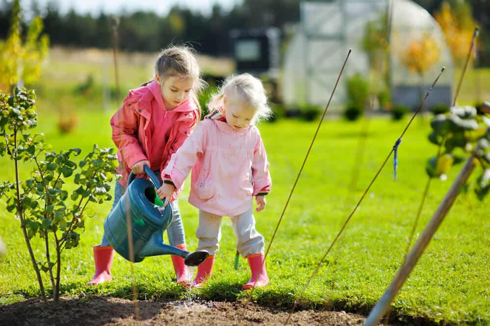 Two little girls watering plants